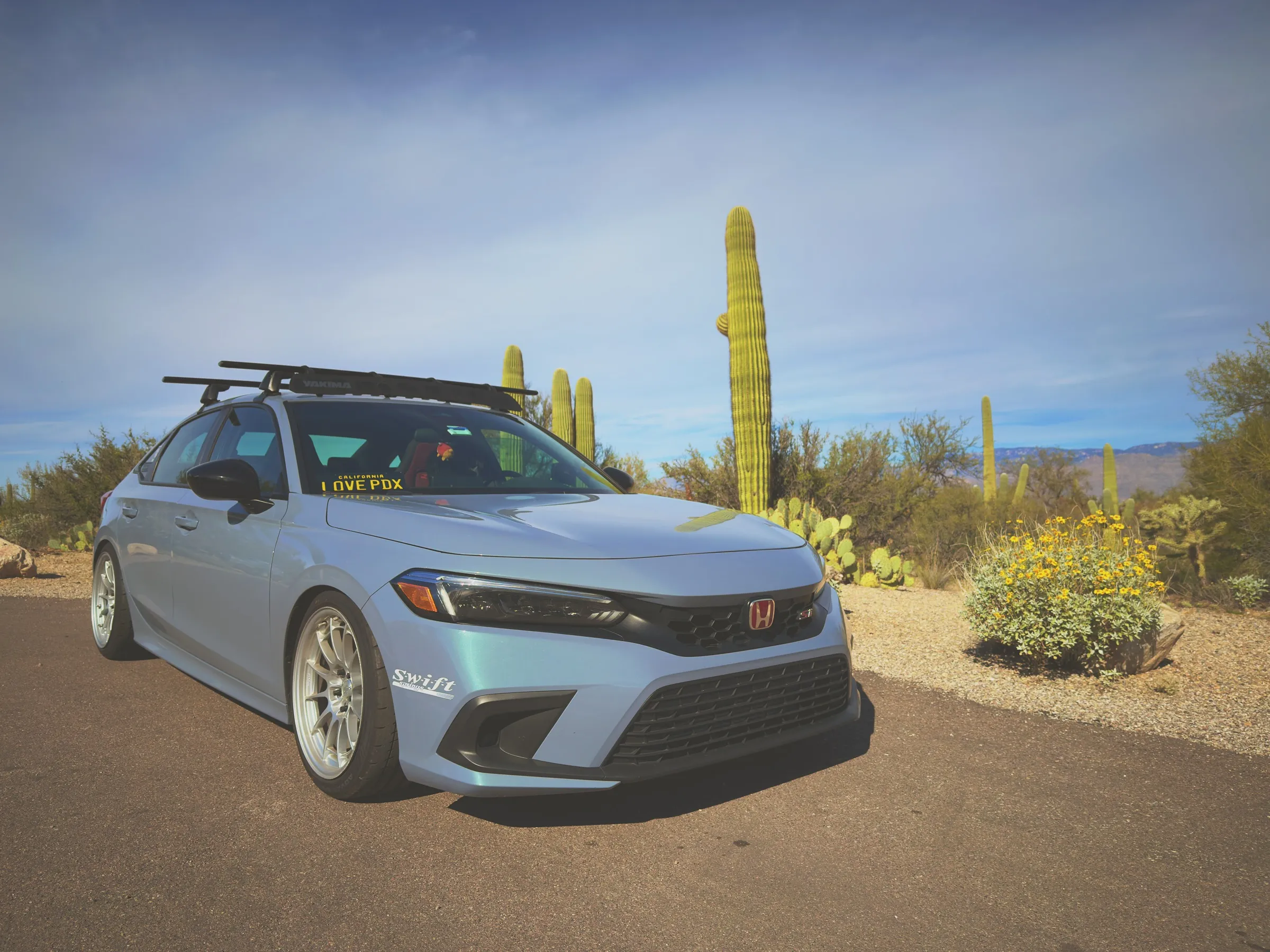 The car parked on a desert road with saguaros all around