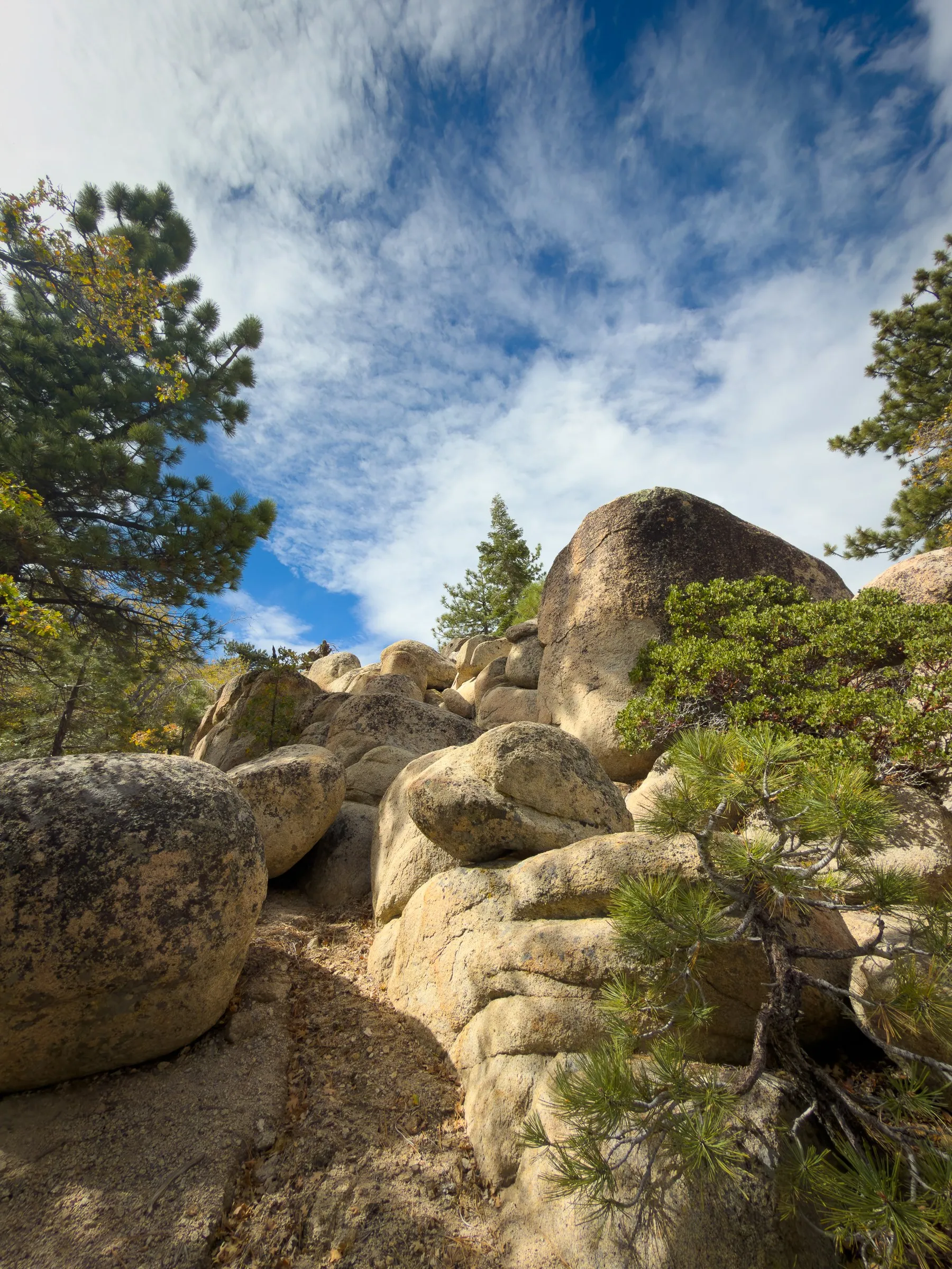 Big rounded granite boulders climbing toward a sky full of clouds